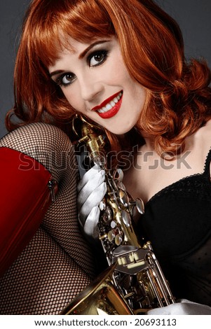Beautiful sexy red-headed smiling girl with saxophone