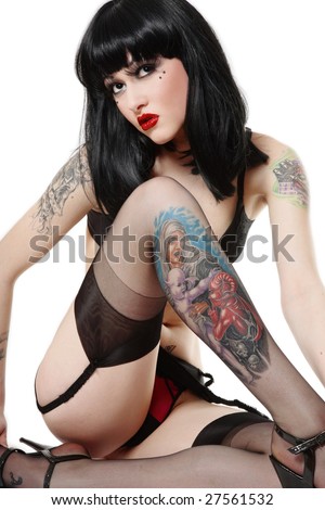  brunette with tattoos sitting in white background and looking upwards