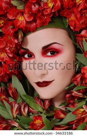 Portrait of beautiful girl with fancy makeup and red flowers around her face