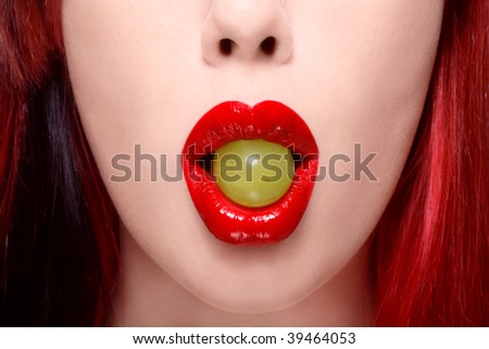 Close-up shot of beautiful woman red lips with green grape, selective focus