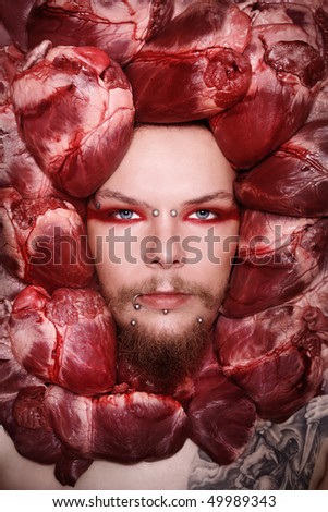 Conceptual close-up portrait of pierced and tattooed man with raw bloody