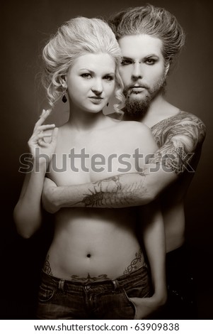 Duotone shot of pierced tattooed man and woman with old-fashioned make-up and hairstyle