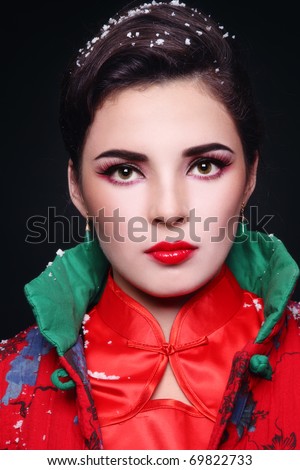 Portrait of beautiful stylish European woman in Chinese clothes with snowflakes on her hair