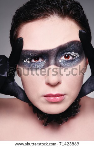 Humorous portrait of young woman with fancy mask painted on her face and incredulous expression