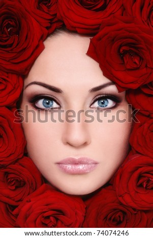 Close-up shot of young beautiful woman face with red roses around