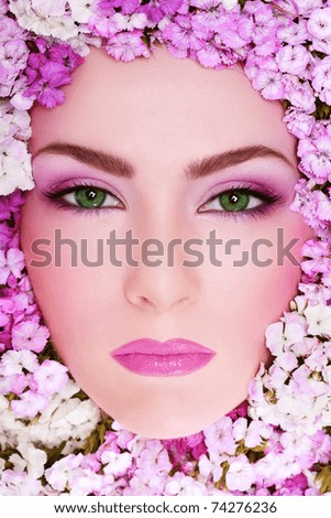 Close-up portrait of beautiful woman with bright makeup and flowers around her face