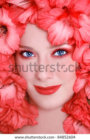 Close-up portrait of beautiful woman with bright make-up and flowers around her face