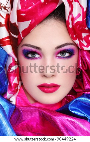 Portrait of young beautiful woman with fancy sparkly make-up and bright fabrics around her face