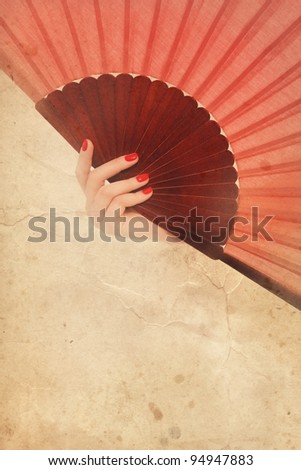 Woman\'s hand with flamenco fan on vintage, grainy, damaged background. Copy space below