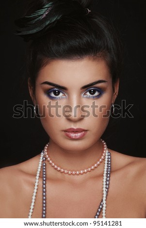 Portrait of young beautiful brunette with stylish make-up and feather in hair