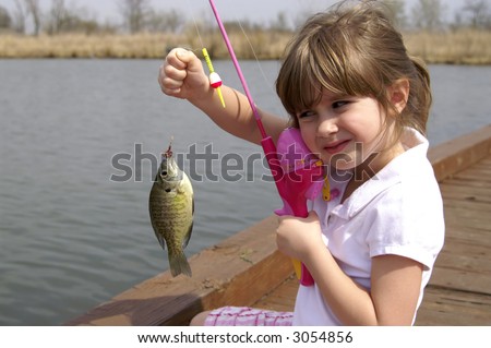 A young girl holding a fish she just caught