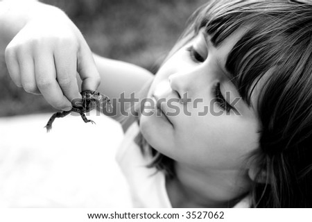 A cute girl holding a toad with shallow depth of field with focus on toad