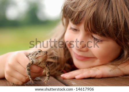 A cute young girl holding a toad