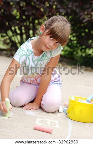 A cute young girl drawing on the sidewalk