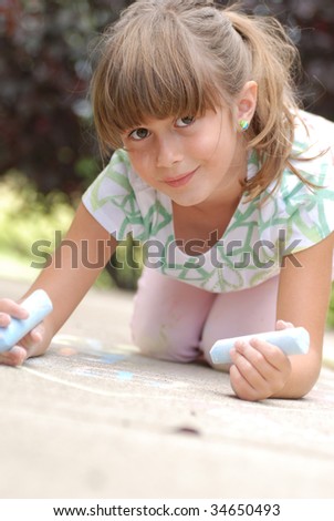 A cute young girl drawing on the sidewalk with chalk