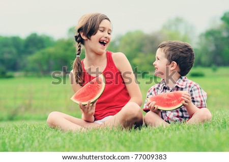 A brother and sister eating watermelon together