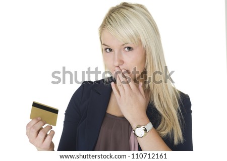 Beautiful blonde woman with a guilty look and her hand to her mouth holding up her credit card on which she has gone on a spending spree and overspent