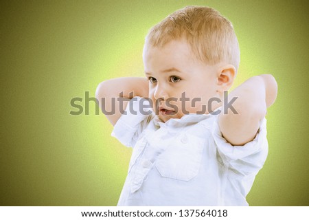Cute handsome little blond boy with raised arms standing looking towards the left of the frame against a graduated green background with vignetting