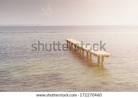 Deserted rustic wooden jetty surrounded by water at high tide or flooding in a calm tranquil ocean with copyspace