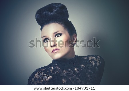 Atmospheric toned retro portrait of a beautiful sophisticated woman with her hair in a bun on top of her head staring dreamily up into the air off to the side