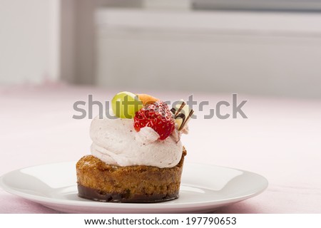 Tasty gourmet dessert with fresh fruit topping on a freshly baked cake and chocolate base with creamy mousse served on a table indoors with copyspace