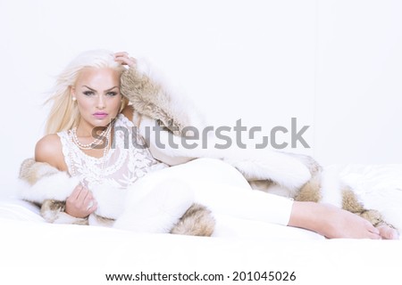 Glamorous female model looking fierce in bed on white background