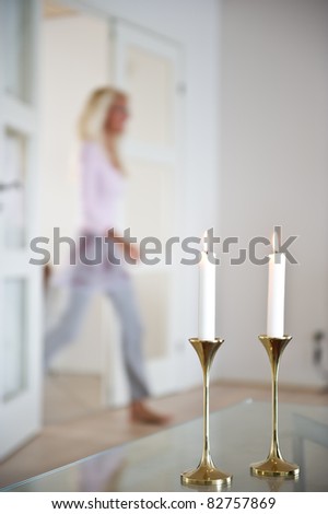 Woman passes through the living room which is illuminated by candle ligts. Out of focus
