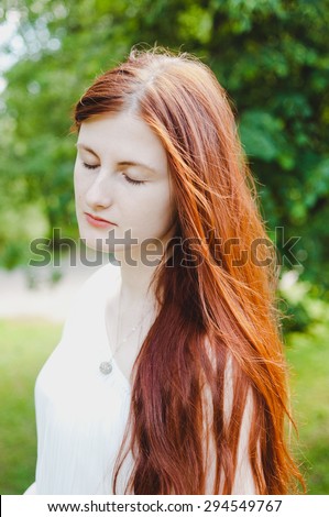 Portrait of a young ginger female with eyes closed representing calmness and peace