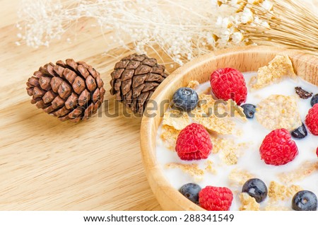 Bowl of cereals with raspberries and blueberrys on a wooden table, healthy breakfast.
