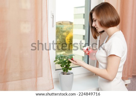 happy young girl sprays a house plant