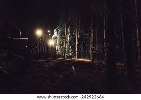 Automated felling forest at night with the help of a harvester closeup