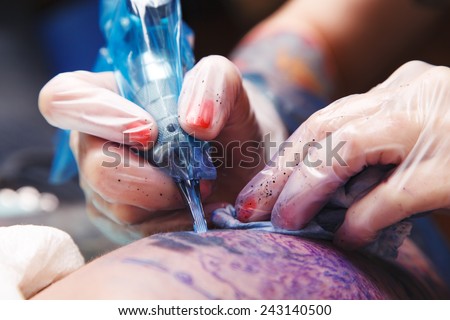 the process of creating a tattoo on the man\'s hand closeup. Machine for tattoos during work closeup