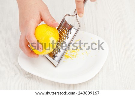rubbing lemon peel grated in a bowl closeup