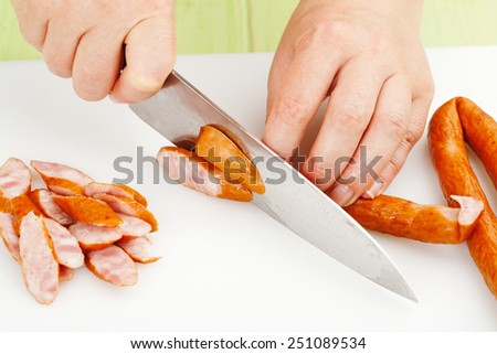 the process of cutting smoked sausage on a cutting board closeup