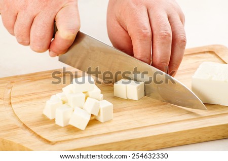the process of cutting the cheese feta on a cutting board closeup