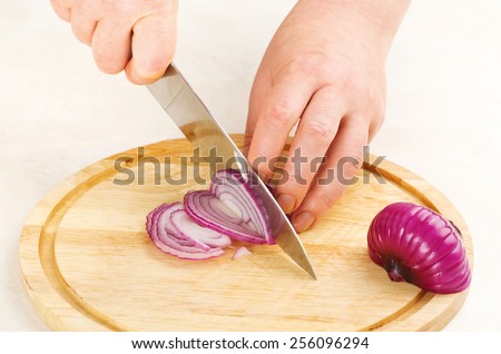 the process of cutting red onion on a cutting board close up