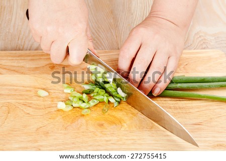 Chef cuts the green onions on a cutting board closeup