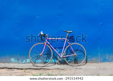 Old hipster bike stands in the blue wall outdoors in summer day. Road bikes standing on a blue wall background brutal