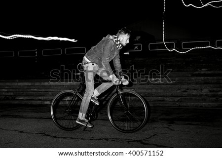 Fashion man on the fixed gear bike rides around the city at night. Black and white