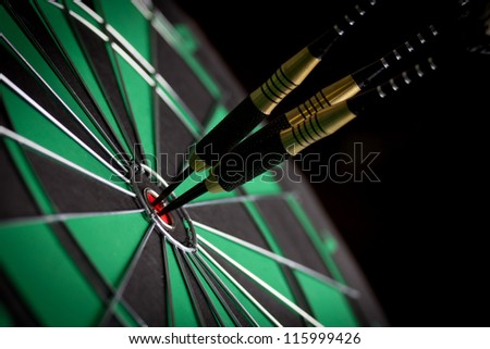 Dart in bulls eye of dartboard with shallow depth of field concept for hitting target