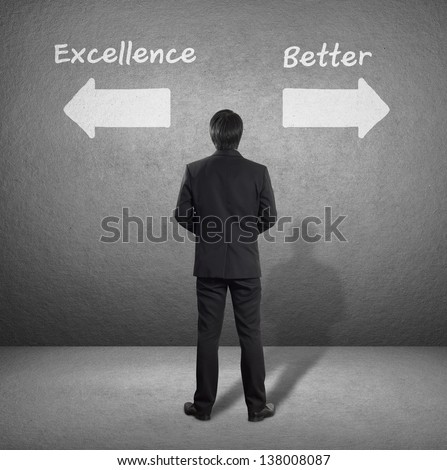 businessman standing in front of two arrows showing two different directions between Excellence or Better