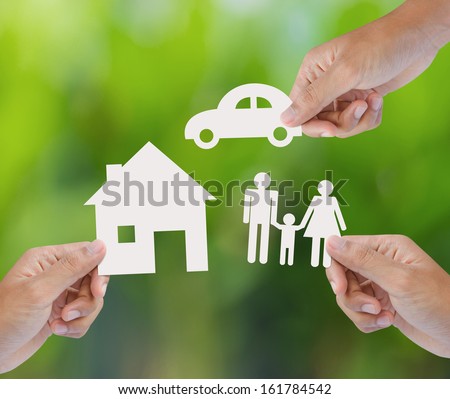 Hand Holding A Paper Home, Car, Family On Green Background, Insurance Concept