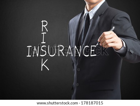 Business man writing Risk Insurance crossword