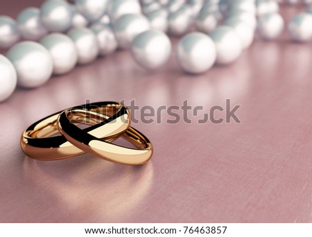 Two golden rings on wood table with pearl beads