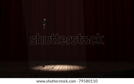 Metallic microphone with cord standing on a wood stage