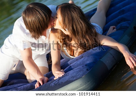 Two young people kissing on the swimming mattress