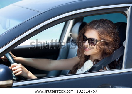 Smiling beautiful brunette woman driving a car