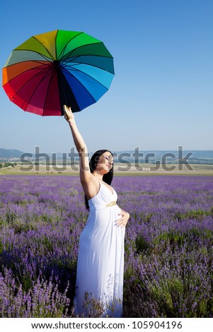 Pregnant woman with colored umbrella in the lavender field