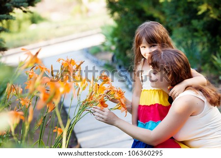 mom and her daughter  play with lilies in the garden