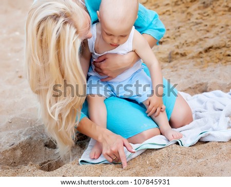 Mother with her baby drawing on the sand